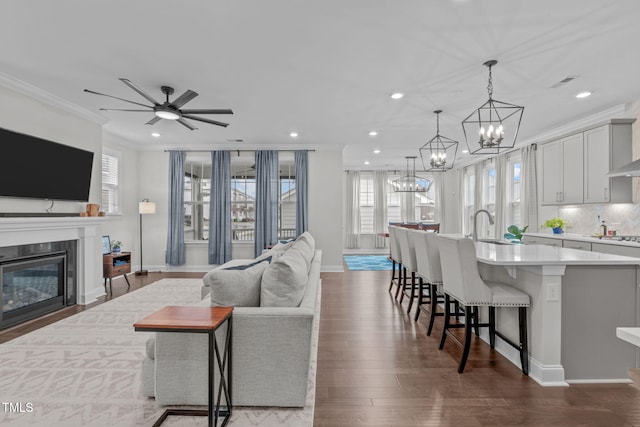 living area with a chandelier, recessed lighting, crown molding, dark wood-style flooring, and baseboards