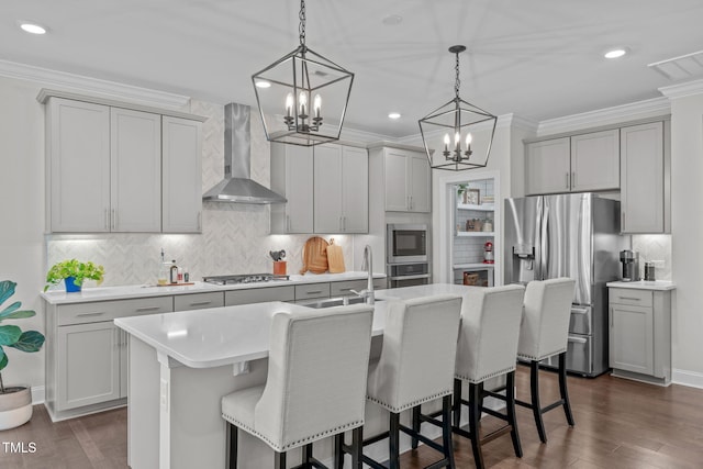 kitchen with wall chimney exhaust hood, stainless steel appliances, a sink, a chandelier, and gray cabinets