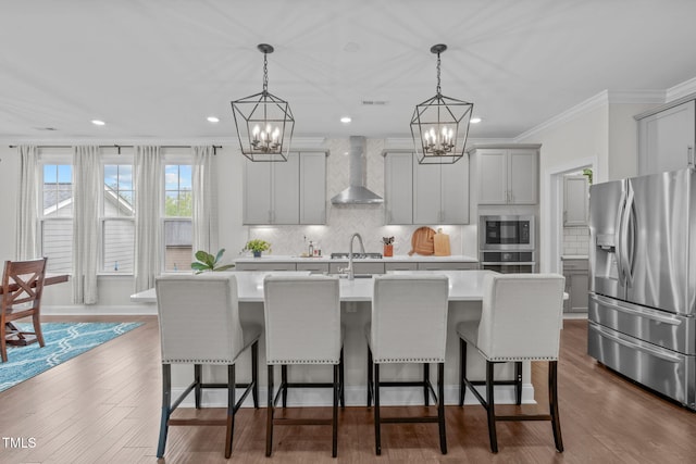 kitchen featuring stainless steel appliances, wall chimney range hood, a chandelier, light countertops, and gray cabinets