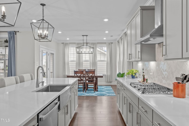 kitchen featuring stainless steel appliances, wall chimney exhaust hood, a chandelier, light countertops, and recessed lighting