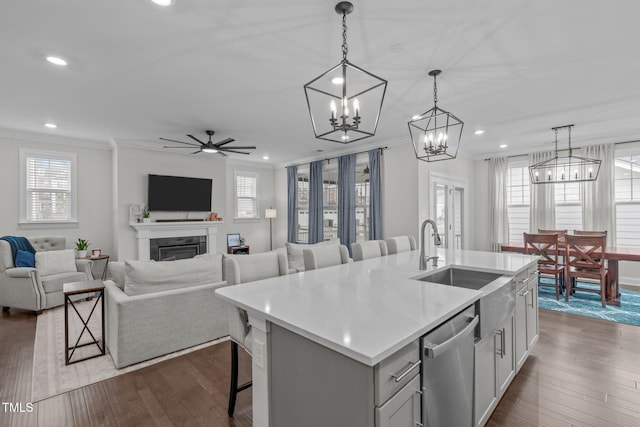 kitchen with stainless steel dishwasher, a chandelier, a sink, a fireplace, and ornamental molding
