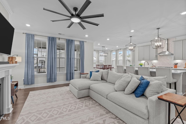 living area with a chandelier, crown molding, recessed lighting, a ceiling fan, and wood finished floors