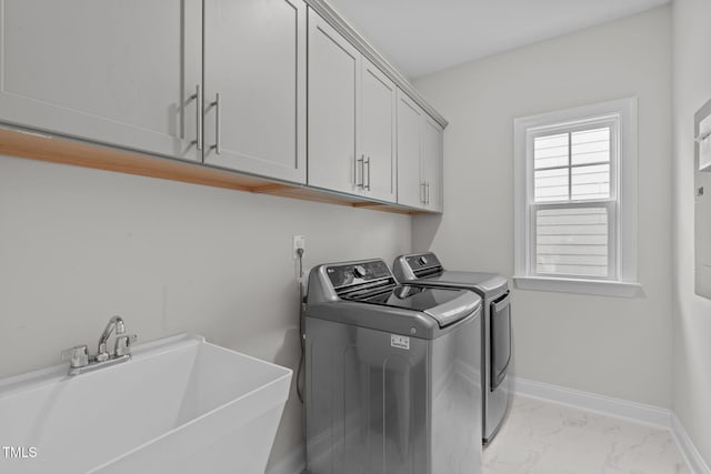 washroom featuring cabinet space, washer and dryer, light marble finish floors, and baseboards