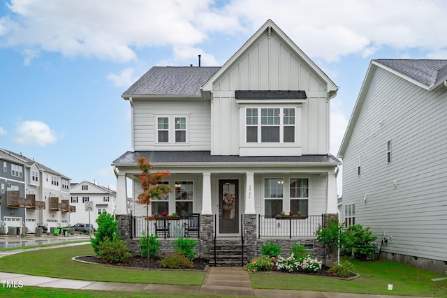 craftsman house with board and batten siding, covered porch, a shingled roof, and a front lawn