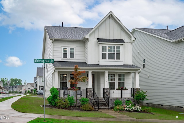 view of front of property featuring board and batten siding, covered porch, a front lawn, and roof with shingles