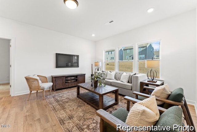 living area with light wood-style flooring, baseboards, and recessed lighting