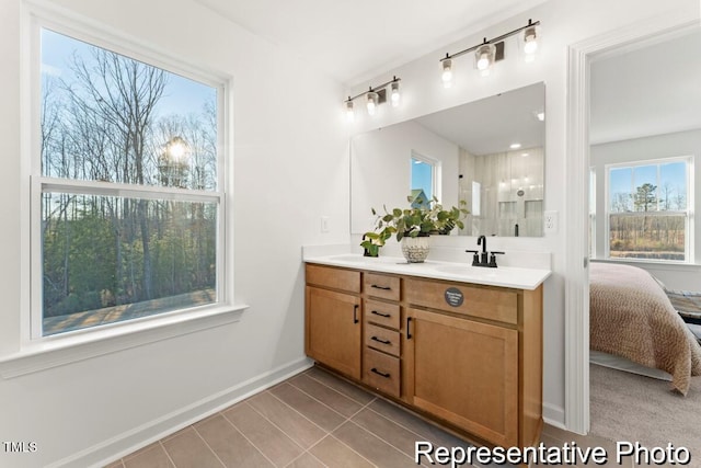 ensuite bathroom featuring double vanity, a sink, tile patterned floors, ensuite bathroom, and baseboards