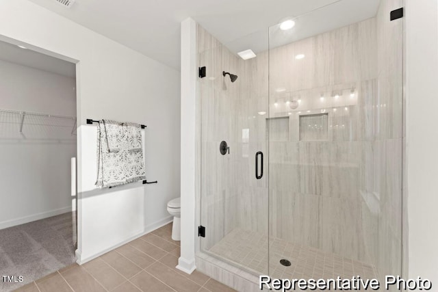 full bath with a stall shower, tile patterned floors, toilet, and a walk in closet