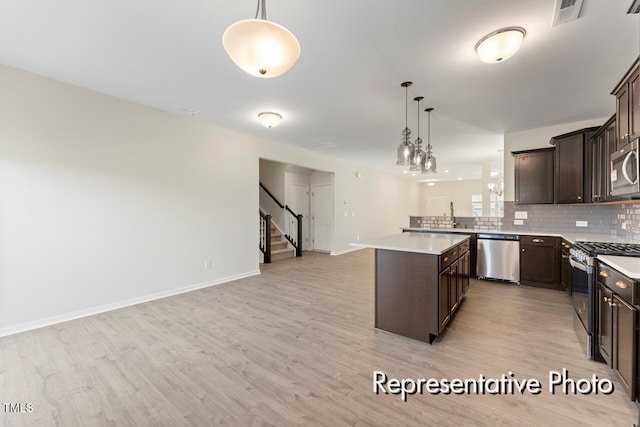 260 Curling Creek Dr Unit 235P, Clayton, NC 27527 - kitchen featuring appliances with stainless steel finishes, open floor plan, dark brown cabinetry, light countertops, and light wood-style floors