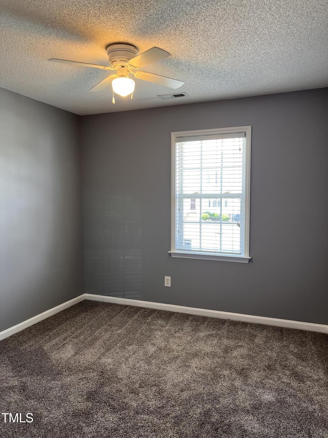 carpeted spare room featuring a textured ceiling, baseboards, a ceiling fan, and visible vents