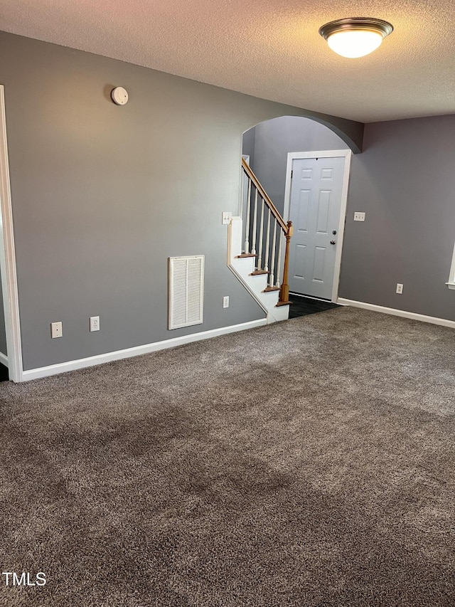 entrance foyer featuring carpet floors, a textured ceiling, arched walkways, and visible vents