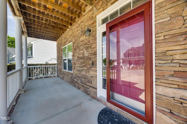property entrance with stone siding and a porch