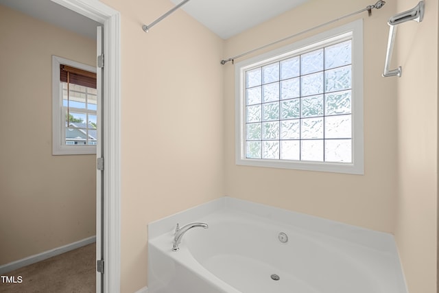 bathroom with a garden tub and baseboards
