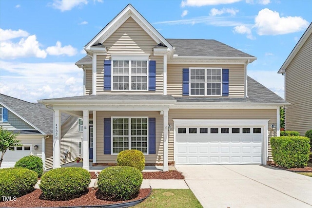 traditional-style house with covered porch, concrete driveway, and a garage
