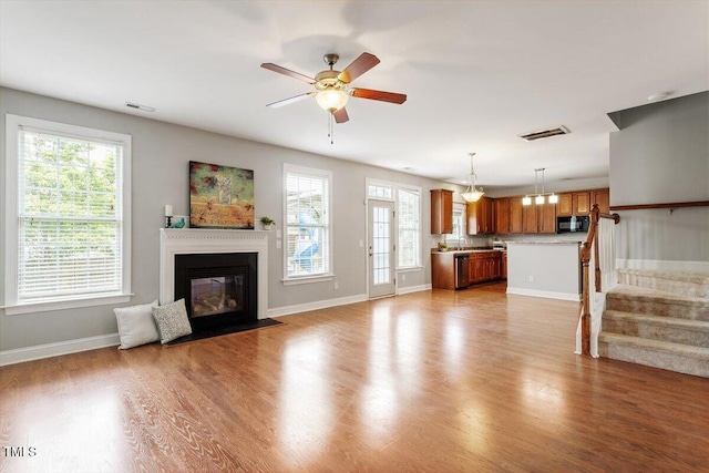 unfurnished living room with a fireplace with flush hearth, wood finished floors, and baseboards
