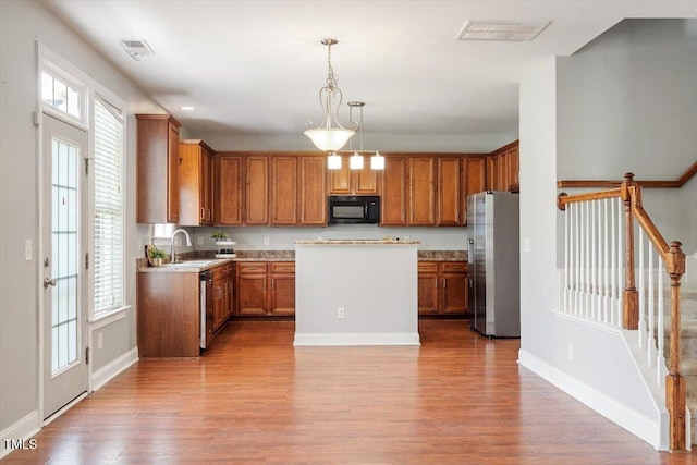 kitchen with stainless steel appliances, light wood finished floors, brown cabinetry, and baseboards