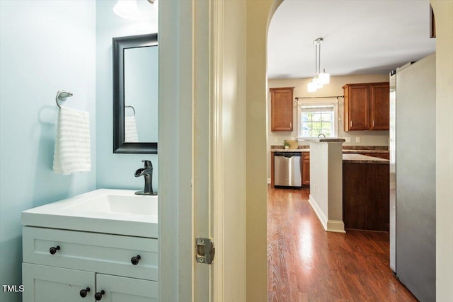 hallway featuring dark wood-style floors, a sink, and arched walkways