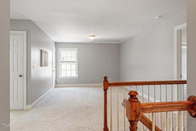 hallway with carpet floors, baseboards, and an upstairs landing