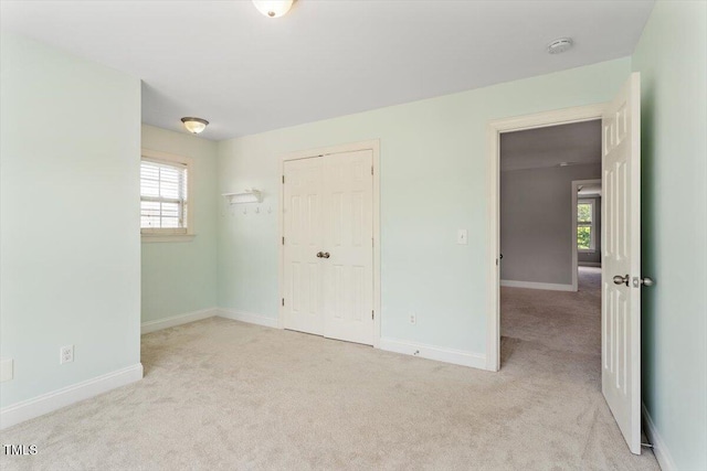 unfurnished bedroom with carpet, multiple windows, and baseboards