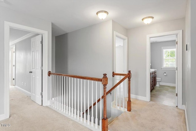 corridor featuring an upstairs landing, carpet floors, and baseboards