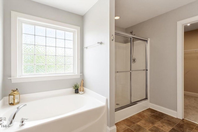 bathroom featuring a stall shower, a garden tub, a spacious closet, and baseboards