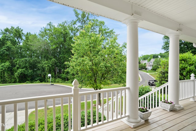 wooden terrace featuring a porch and view of wooded area