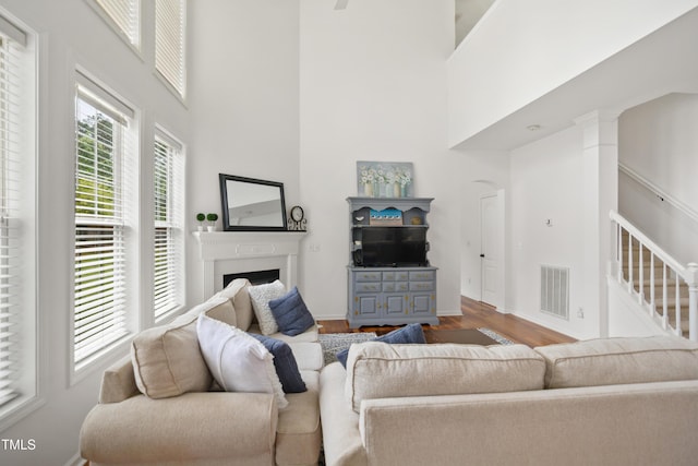 living room featuring wood finished floors, a high ceiling, a fireplace, stairs, and baseboards