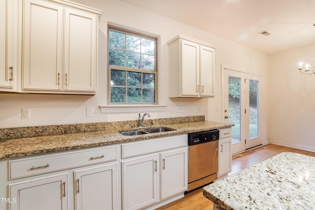 kitchen with stainless steel dishwasher, light wood-style flooring, light stone countertops, and a sink