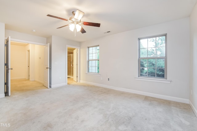 unfurnished bedroom featuring light colored carpet, visible vents, a ceiling fan, connected bathroom, and baseboards