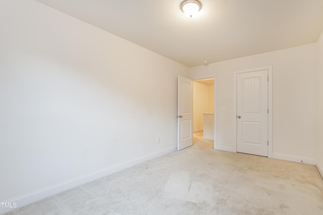 unfurnished bedroom featuring light carpet and baseboards