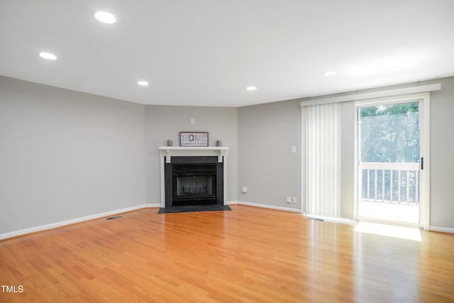 unfurnished living room featuring light wood-type flooring, recessed lighting, a fireplace with flush hearth, and baseboards