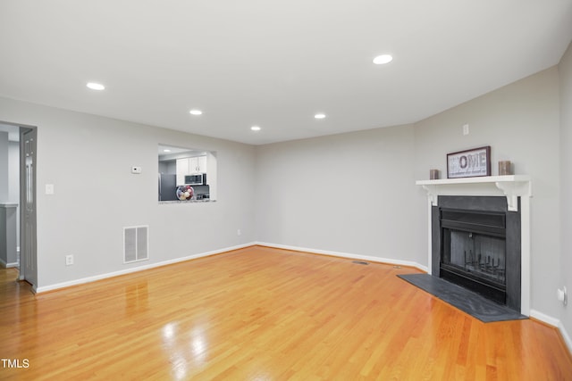 unfurnished living room with a fireplace, light wood-style flooring, baseboards, and recessed lighting