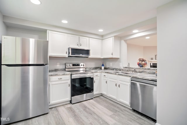 kitchen featuring appliances with stainless steel finishes, a sink, white cabinets, and recessed lighting
