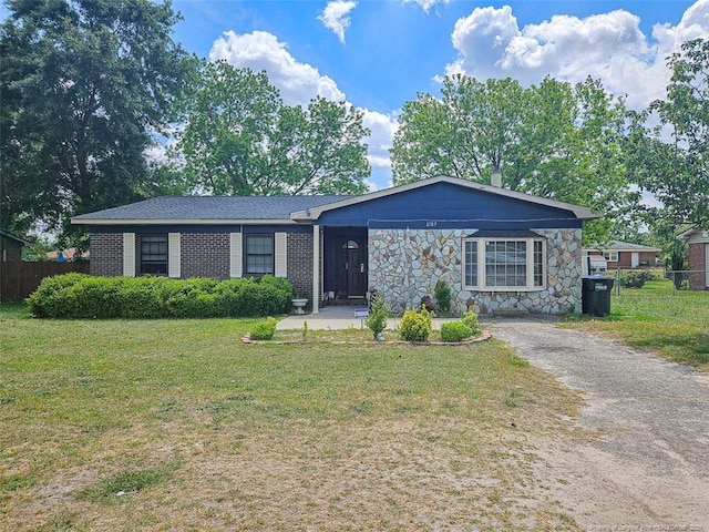single story home featuring fence, stone siding, and a front yard