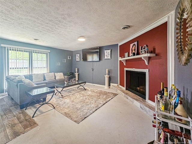 living room with a textured ceiling, baseboards, concrete floors, and a fireplace with raised hearth