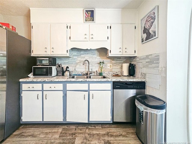 kitchen with light countertops, stainless steel appliances, white cabinets, and a sink
