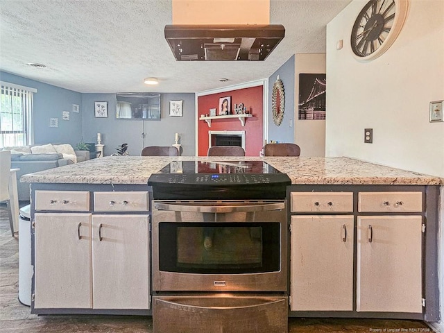 kitchen featuring a fireplace, a textured ceiling, stainless steel range with electric stovetop, and open floor plan
