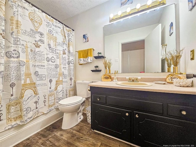 full bath featuring toilet, wood finished floors, vanity, and a textured ceiling