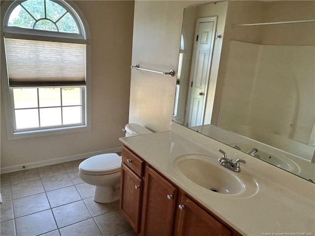 bathroom with toilet, baseboards, tile patterned floors, vanity, and a shower