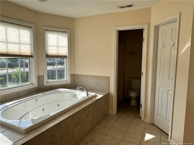 bathroom featuring toilet, visible vents, tile patterned flooring, and a jetted tub