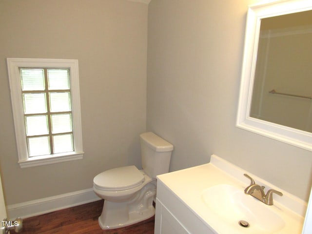 half bathroom with toilet, baseboards, wood finished floors, and vanity