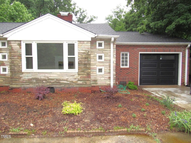 view of front facade featuring an attached garage, stone siding, crawl space, a chimney, and a shingled roof