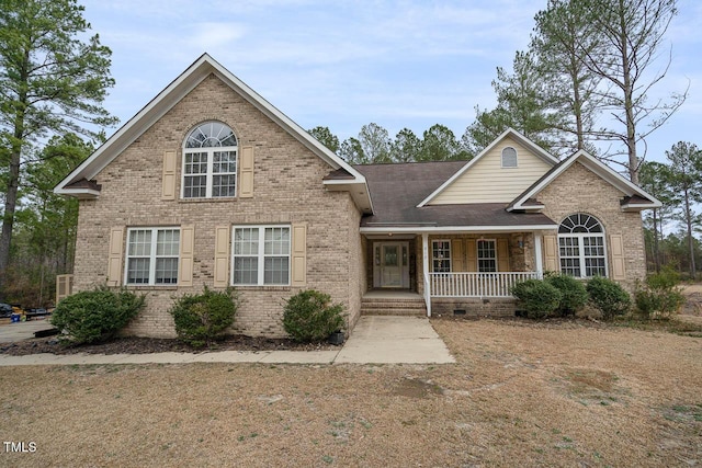 view of front of home with brick siding, roof with shingles, and a porch