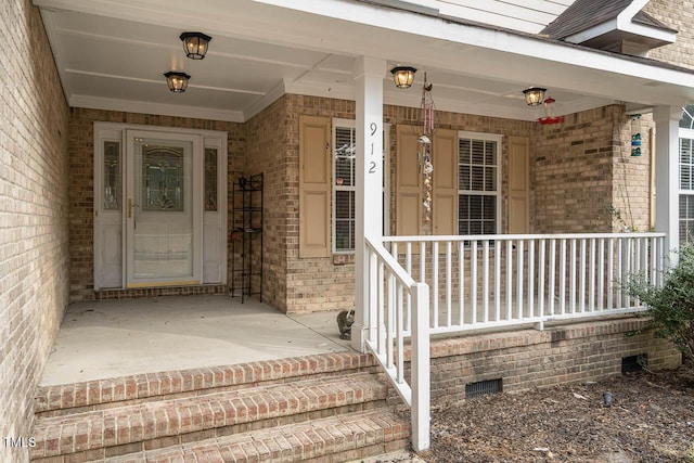 doorway to property with covered porch and brick siding