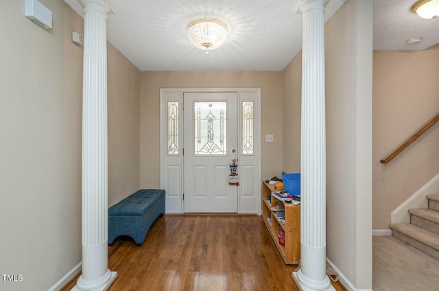 foyer entrance featuring wood finished floors, baseboards, decorative columns, and stairs