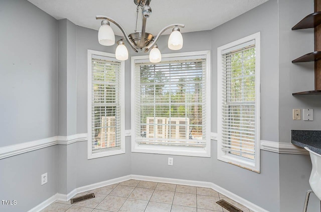 unfurnished dining area featuring an inviting chandelier, light tile patterned flooring, baseboards, and visible vents