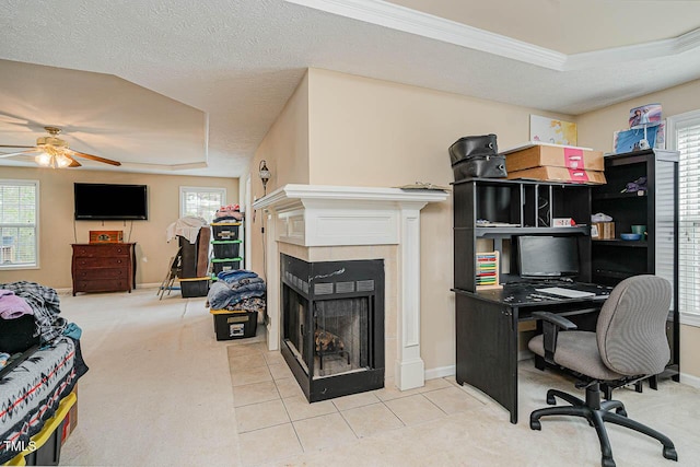 carpeted home office with a tile fireplace, baseboards, a raised ceiling, and ceiling fan