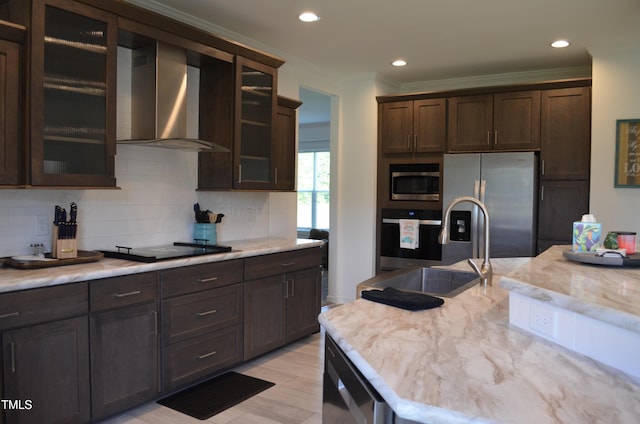 kitchen featuring dark brown cabinets, crown molding, wall chimney range hood, stainless steel appliances, and tasteful backsplash