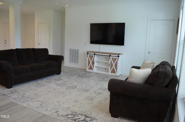 living area with baseboards, crown molding, visible vents, and wood finished floors