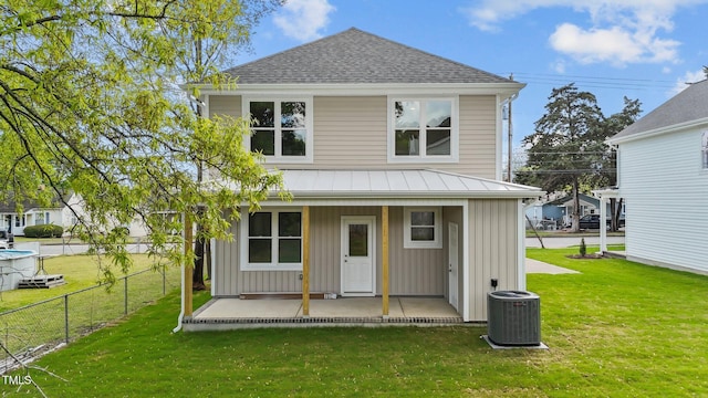 back of property with fence, a yard, cooling unit, board and batten siding, and a shingled roof
